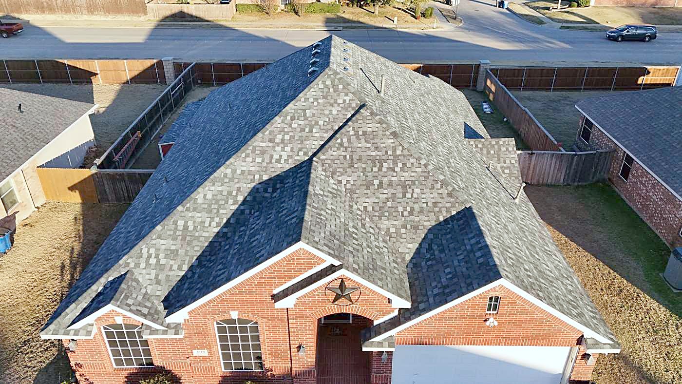 Drone view of a red brick home with a star on the gable and a new gray shingle roof