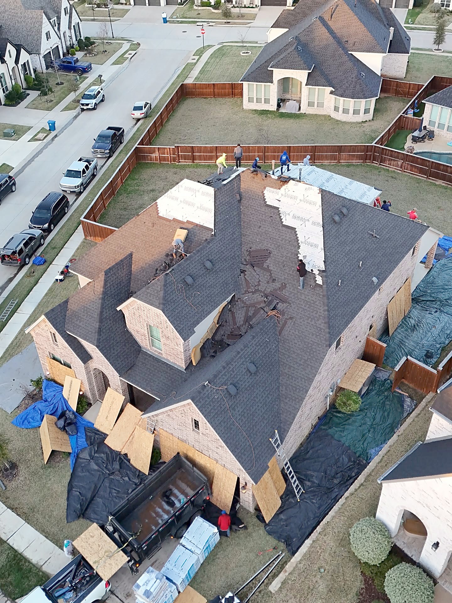 Drone view of a roof mid tear-off with new decking, underlayment and a crew on the roof