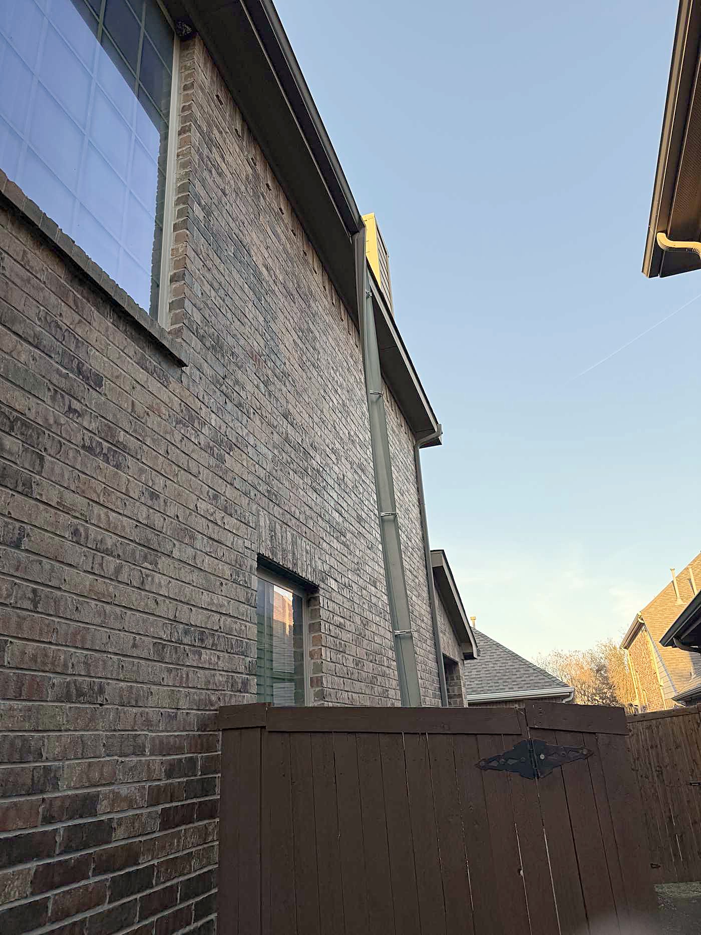 A downspout running down a two story brick wall